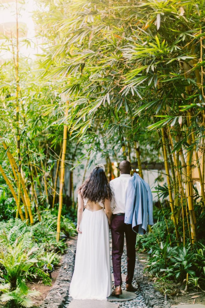 Tim & Angela walk through a lush bamboo landscape on the day of their Maui wedding.